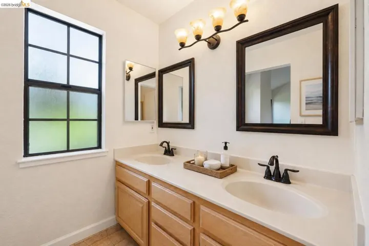 Double vanity with integrated sinks, light-toned countertops, and wood-finish cabinetry