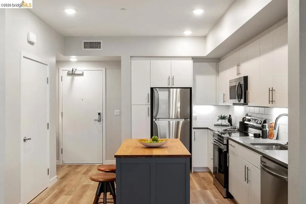 Kitchen featuring appliances with stainless steel finishes, light wood-style floors, white cabinetry, backsplash, and recessed lighting