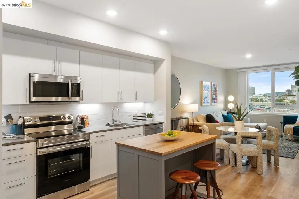 Kitchen featuring stainless steel appliances, open floor plan, butcher block counters, tasteful backsplash, and light wood finished floors