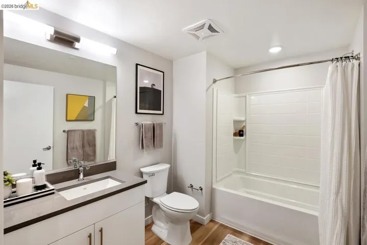 Bathroom featuring shower / bath combo with shower curtain, light wood-type flooring, and vanity