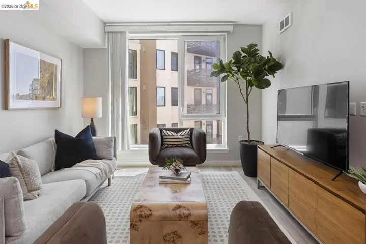 Living area featuring large windows, wood-finish flooring, a light-colored area rug, a built-in media console, and recessed lighting