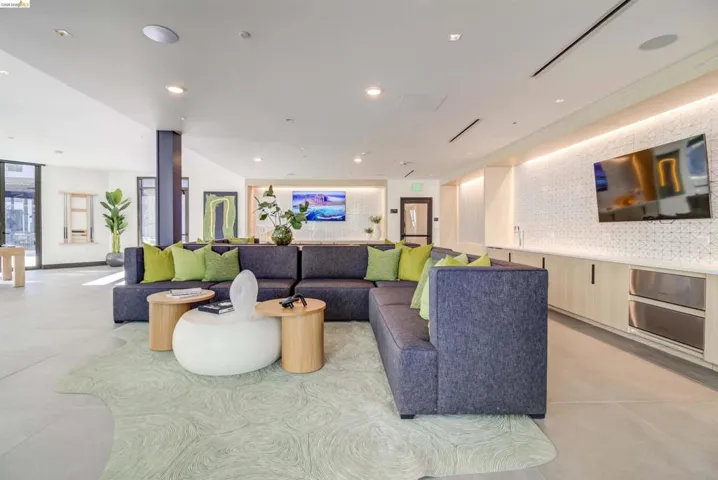 Spacious common area featuring large format tile flooring, a built-in media console with integrated refrigeration, and recessed lighting