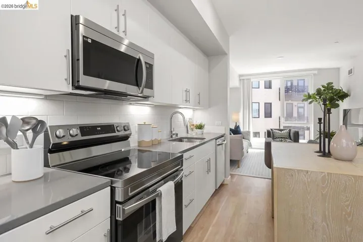 Kitchen featuring white cabinetry, stainless steel appliances, solid surface countertops, a white subway tile backsplash, and light wood-finish flooring