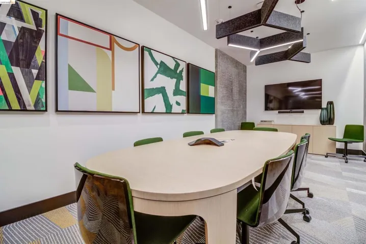 Conference room featuring a large oval table, integrated modern lighting, a mounted display screen, built-in cabinetry, and patterned carpet