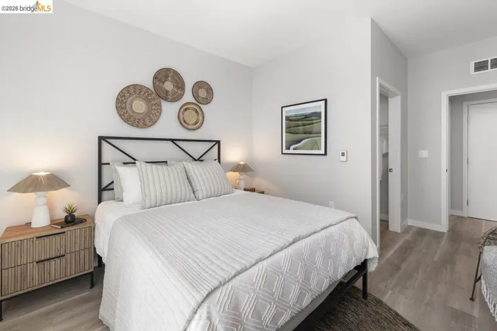 Light-filled bedroom featuring light-toned walls, wood-finish flooring, and a contemporary metal headboard