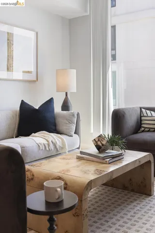Bright living space featuring a large window, light-colored walls, and patterned carpeting