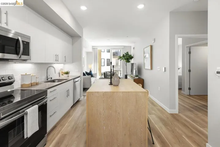 Modern kitchen featuring stainless steel appliances, white cabinetry with brushed nickel hardware, light-toned countertops, and a subway tile backsplash