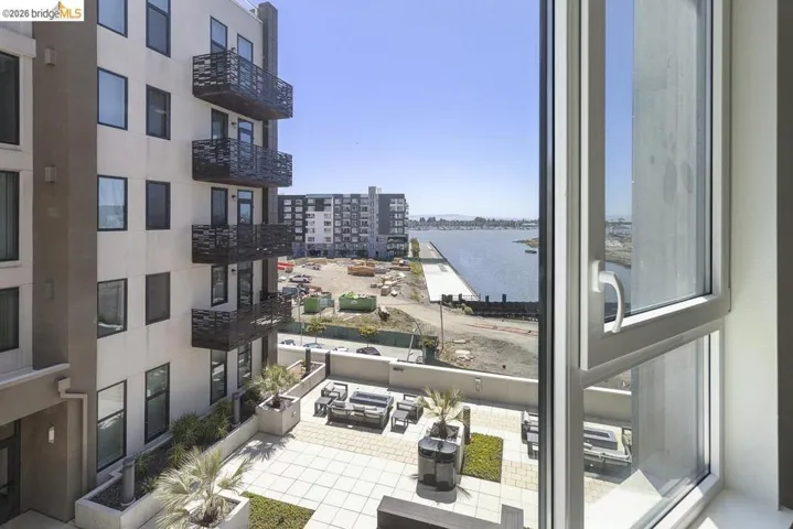Expansive water views and a modern courtyard with a tiled patio are visible from the large window