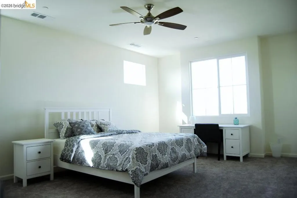 Spacious room featuring a ceiling fan, a large window, a smaller upper window, and light-colored walls