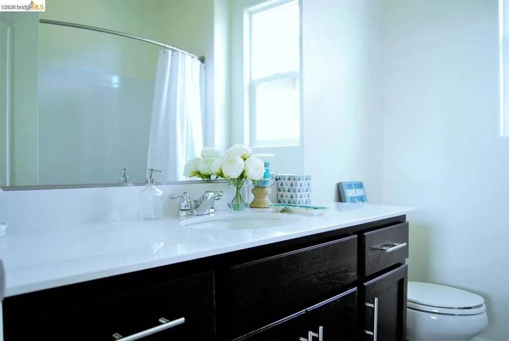 Bathroom featuring a dark wood-finish vanity with chrome hardware, an integrated sink, and a white countertop