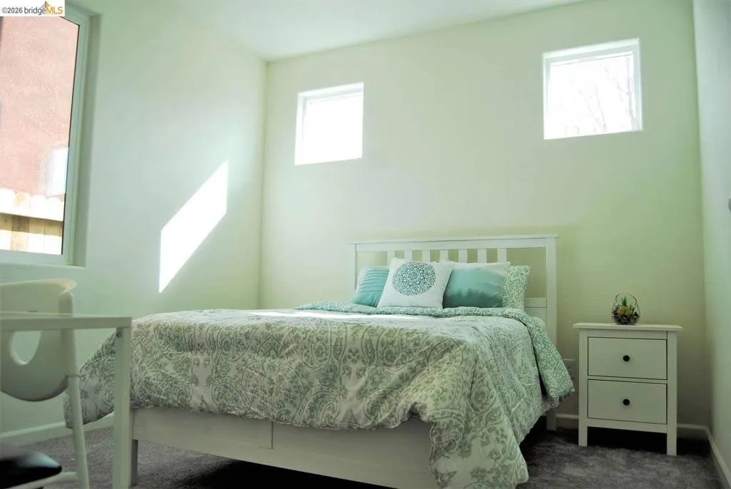 Carpeted room featuring a large window, two transom windows, and light-toned walls