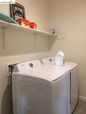 Dedicated laundry area featuring white top-load appliances and a wall-mounted shelving unit