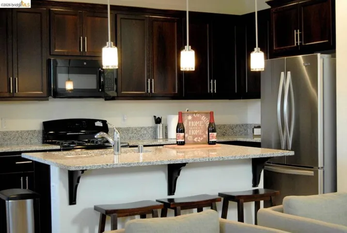 Kitchen featuring dark wood cabinetry, light speckled countertops, and stainless steel appliances