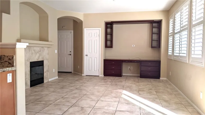 Living rm has tiled floors, fireplace, shutters, built-in desk