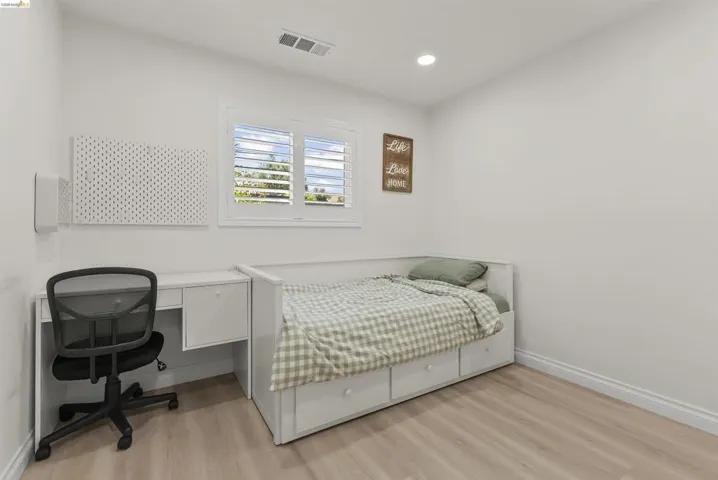 Bedroom featuring wood-finish flooring, recessed lighting, and a window with plantation shutters