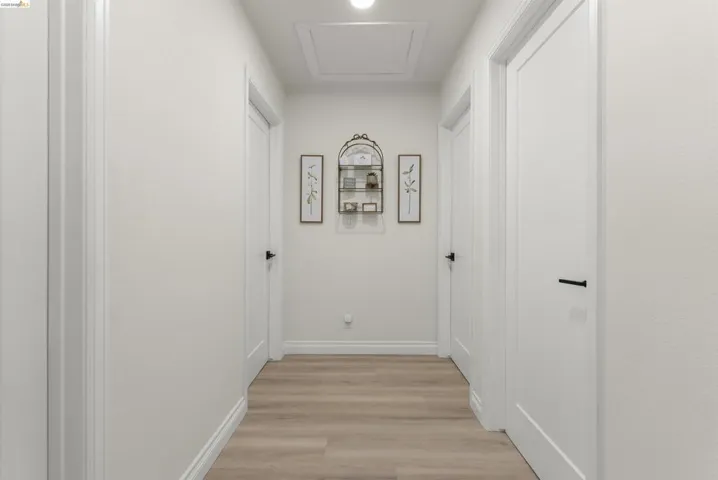 Hallway with light wood-finish flooring, white walls, and bright white trim