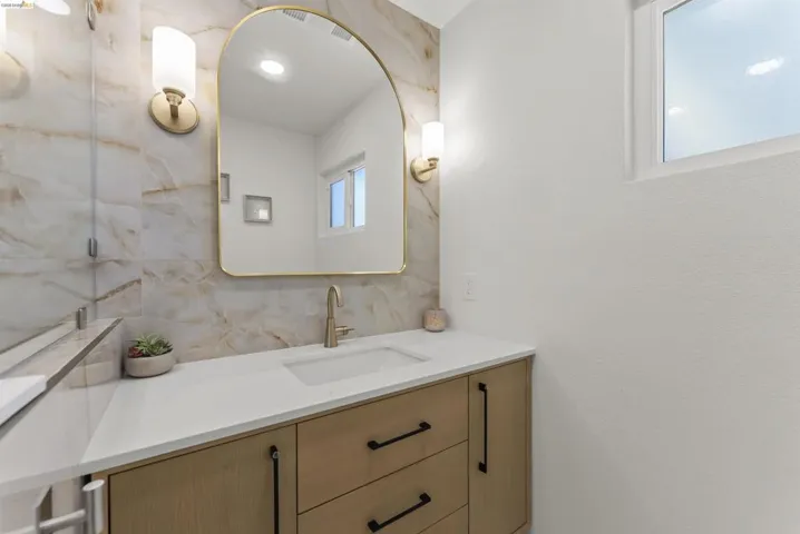 Bathroom vanity featuring a quartz countertop, integrated sink, and brushed brass faucet