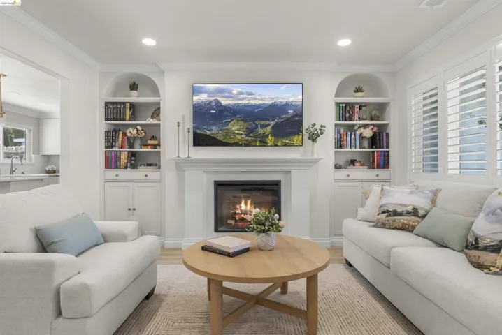 Living area featuring a central fireplace with a mantel, flanked by built-in arched bookcases with lower cabinetry