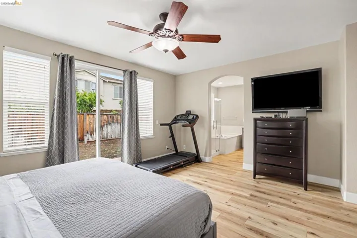 Spacious room featuring wood-finish flooring, a ceiling fan with light, and direct backyard access through sliding glass doors
