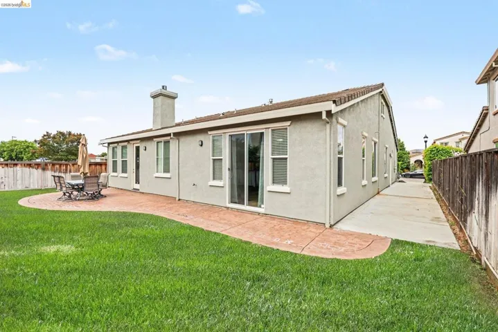 Expansive backyard featuring a manicured lawn, a stamped concrete patio, and a concrete pathway