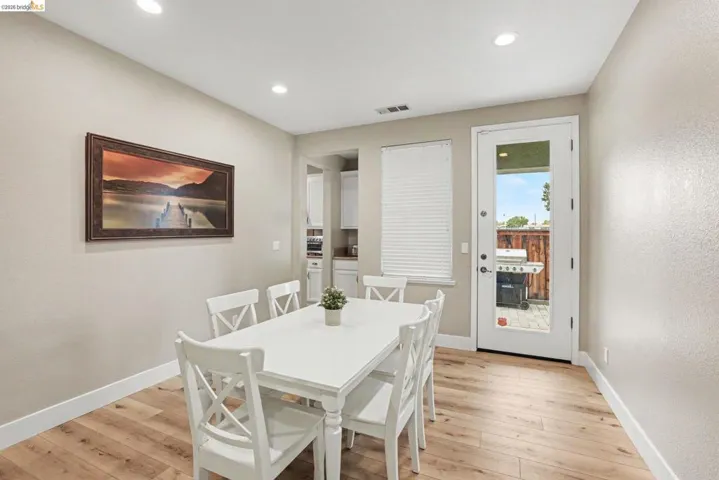 Open-concept dining area featuring wood-finish flooring, recessed lighting, and a full-light door providing exterior access