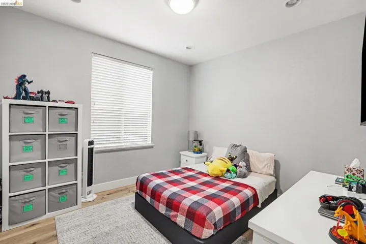Bedroom featuring wood-finish flooring, recessed lighting, and a window with blinds