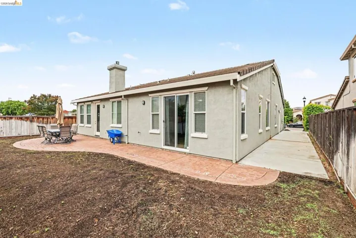 Expansive backyard featuring a stamped concrete patio, a concrete side path, and stucco exterior