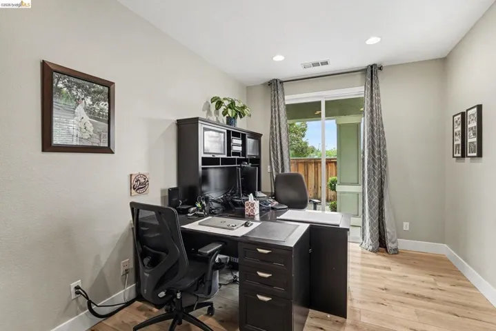Spacious room featuring wood-finish flooring, recessed lighting, and a sliding glass door