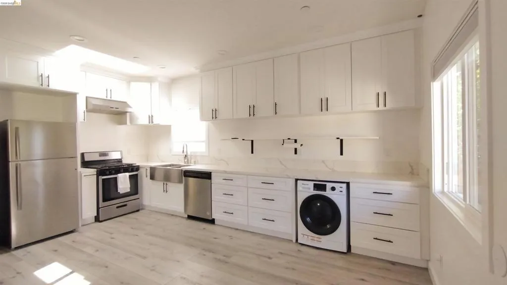 Kitchen featuring white cabinets, stainless steel appliances, washer / clothes dryer, and light wood finished floors