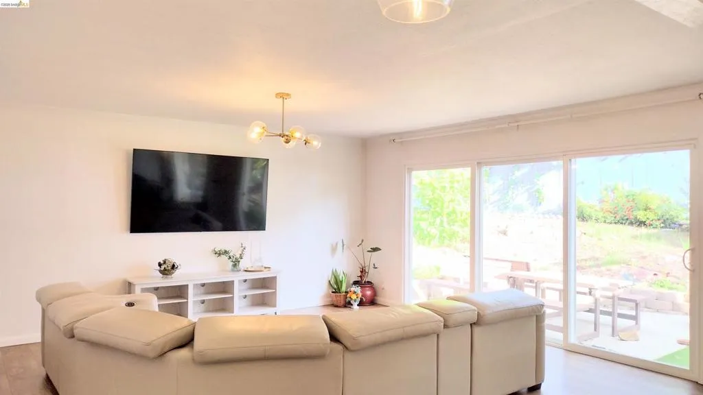 Living room featuring wood finished floors, a chandelier, and crown molding