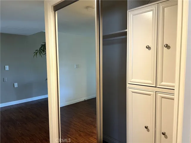 Large closet in the hall has mirrored closet doors.  There are shelves on one side and a clothing rod on the opposite side.