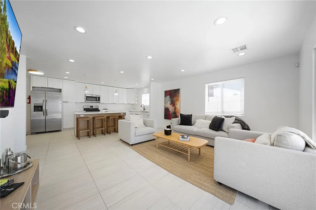 Living room with tile flooring, recessed lighting, double pane window and slider. Furniture remains. Art on wall is excluded. Opens to kitchen and dining.