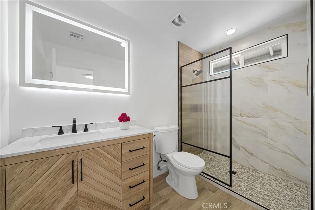 Primary en suite has been beautifully updated with light emitting from the mirror and a walk in shower and nice chevron design at the cabinet/sink.