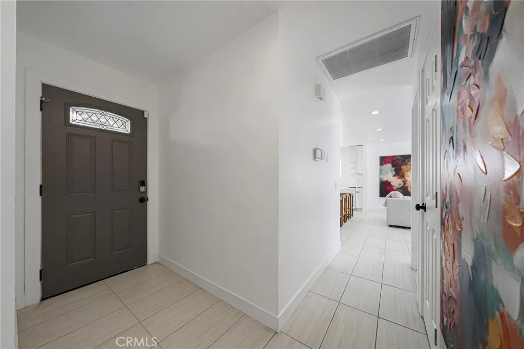 Formal entry. Hallway angle looking towards the living area. One of the four bedrooms to the right. Art on walls in the image are not included.
