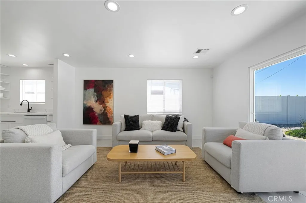 Living room with tile flooring, recessed lighting, double pane window and slider. Furniture remains. Art on wall is excluded.