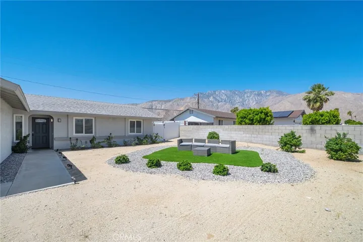 Roomy frontward with turf and rock island. Furniture remains. View of San Jacinto mountains.