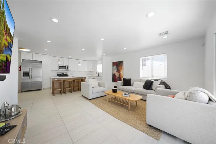 Living room with tile flooring, recessed lighting, double pane window and slider. Furniture remains. Art on wall is excluded. Opens to kitchen and dining.