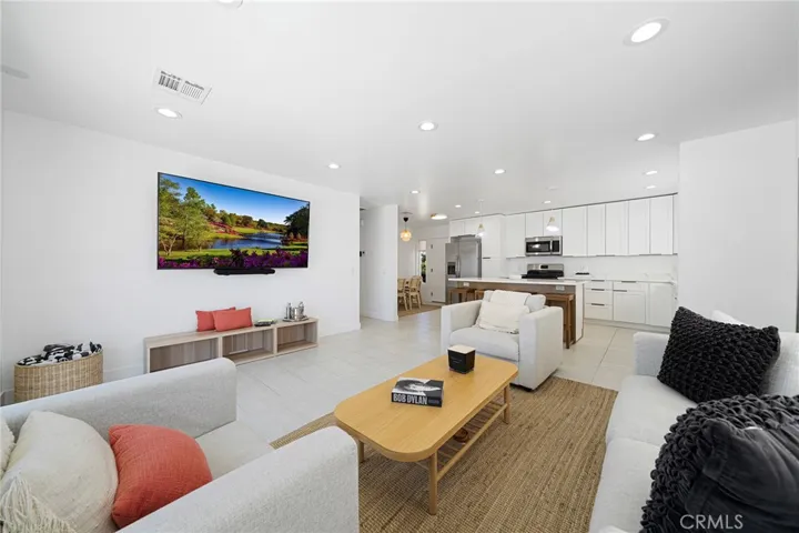 Living room with tile flooring, recessed lighting, double pane window and slider. Furniture remains. Art on wall is excluded. Opens to kitchen and dining.