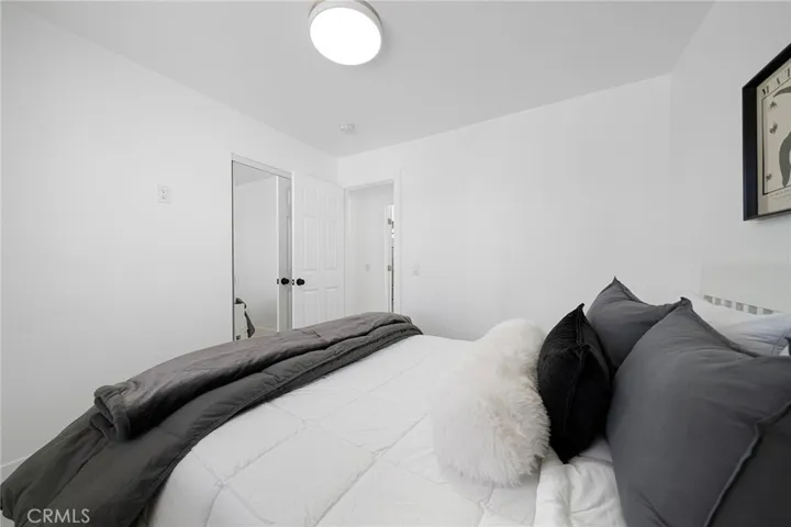 Bedroom at the front end corner of the home with tile flooring, double pane window and view of the front yard. Furniture remains.
