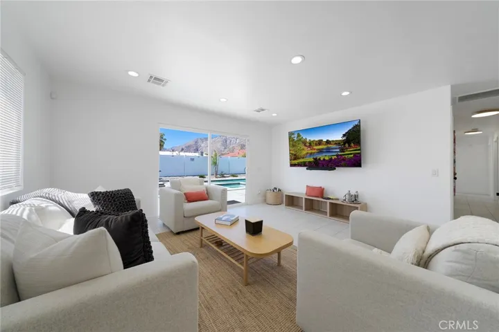 Spacious updated living room with tile flooring and recessed lighting and double pane windows/slider. Furniture remains.