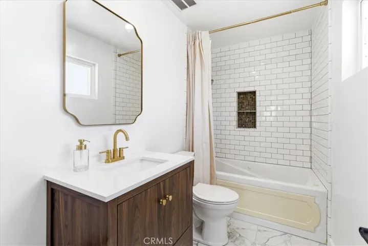 Full bathroom with contemporary vanity, marble countertop, and walk-in shower with glass door.