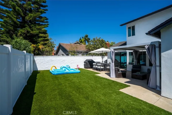 Backyard view showing patio, lawn, and neighboring homes.