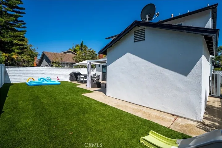 Exterior backyard perspective showing covered patio, lawn, and home structure