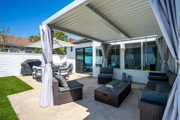 Covered backyard patio with seating, green lawn, and privacy fencing