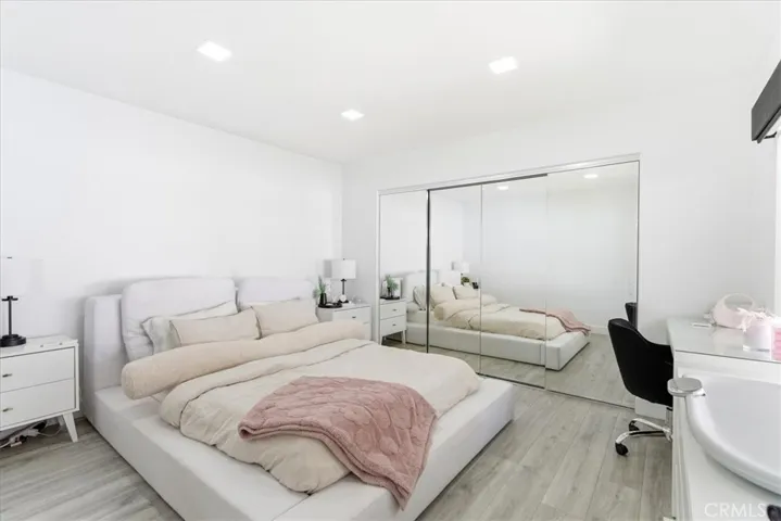 Primary bedroom with large mirrored closet doors, plush carpeting, and bright windows.