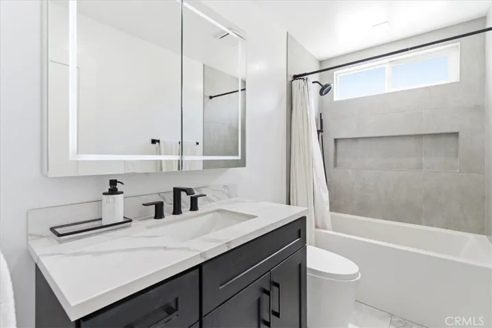 Full bathroom featuring modern vanity, sleek faucet, and tub/shower combination.