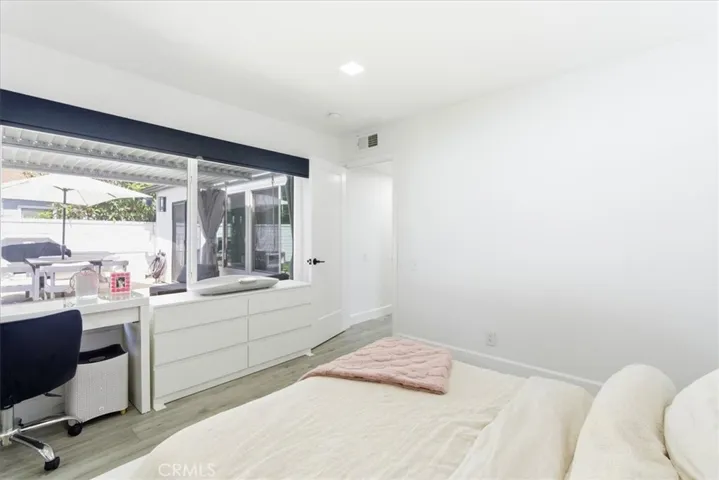 Primary bedroom shown from alternate angle, highlighting mirrored closet doors, plush carpeting, and bright natural light from windows