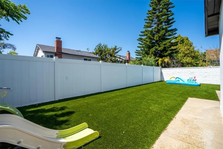 Wide view of backyard lawn with fenced open space.