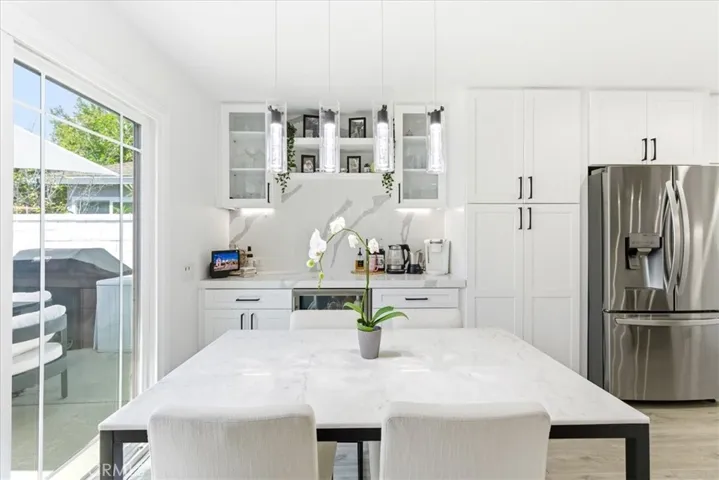 Bright dining area with marble table, modern pendant lighting, stainless steel appliances, and sliding doors leading to the backyard.
