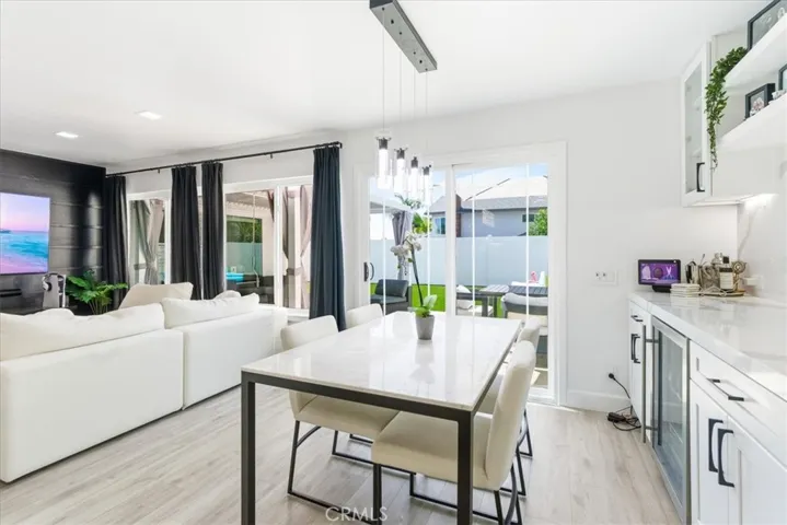 Wide-angle view of the open living and dining area with white sectional sofa, marble dining table, and sliding doors leading to the backyard.